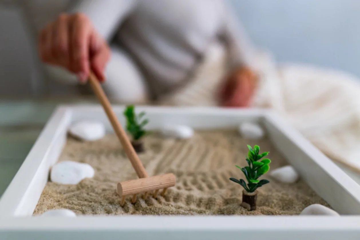 japanese wisdom-hand-of-woman-using-zen-garden-at-home
